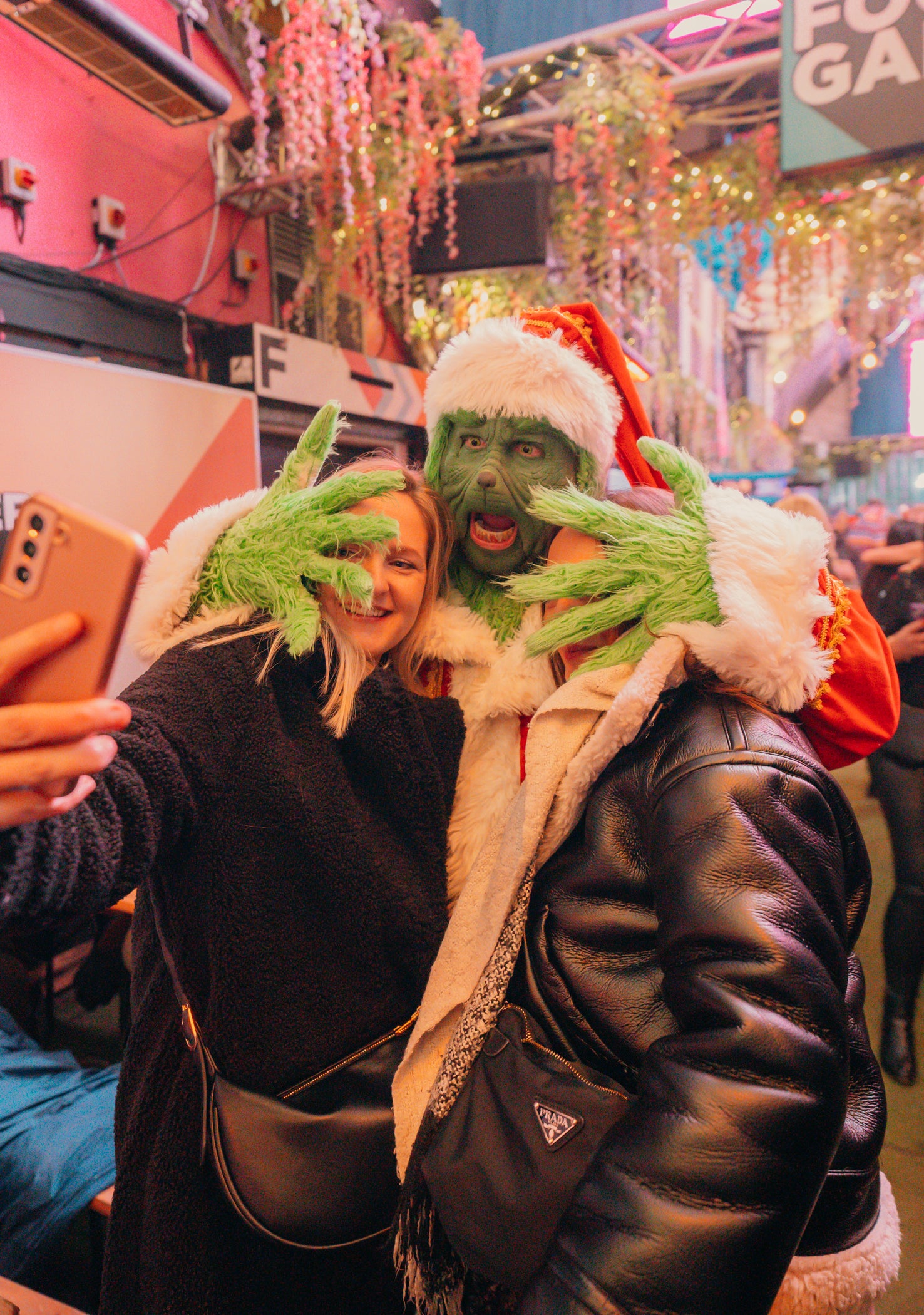 Two people in festive costumes with green face paint and the grinch Santa hats taking a selfie.