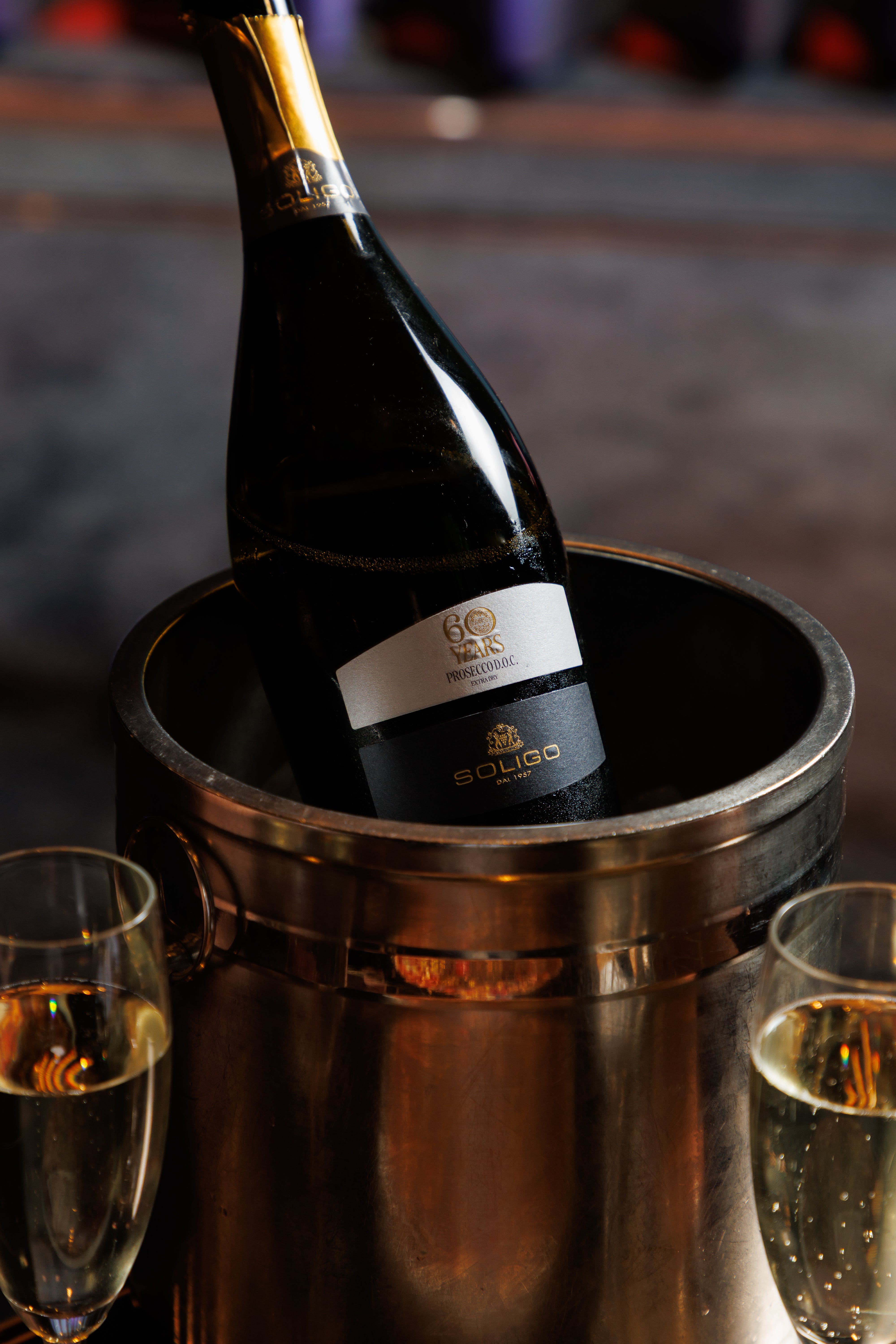Wine bottle in an ice bucket with two glasses on a reflective surface